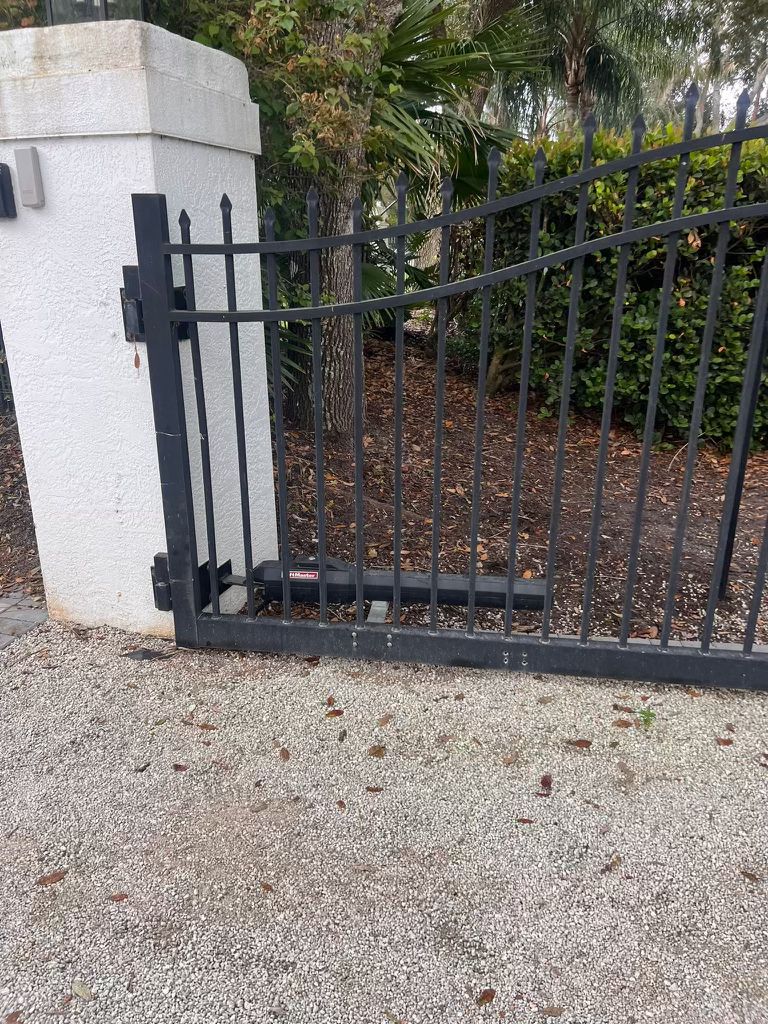 Automatic black metal gate with opener on white pillar in Los Angeles, CA