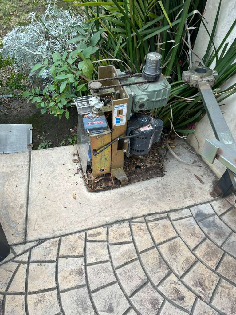 Gate motor and opener mechanism with surrounding foliage and concrete patio. in Los Angeles, CA