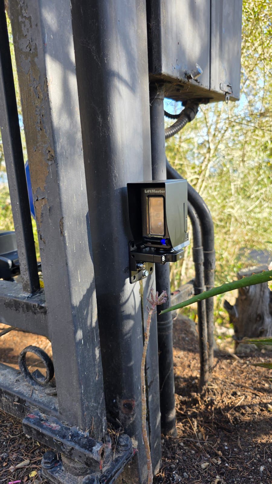 LiftMaster safety sensor mounted on a metal gate post for gate repair. in Los Angeles, CA