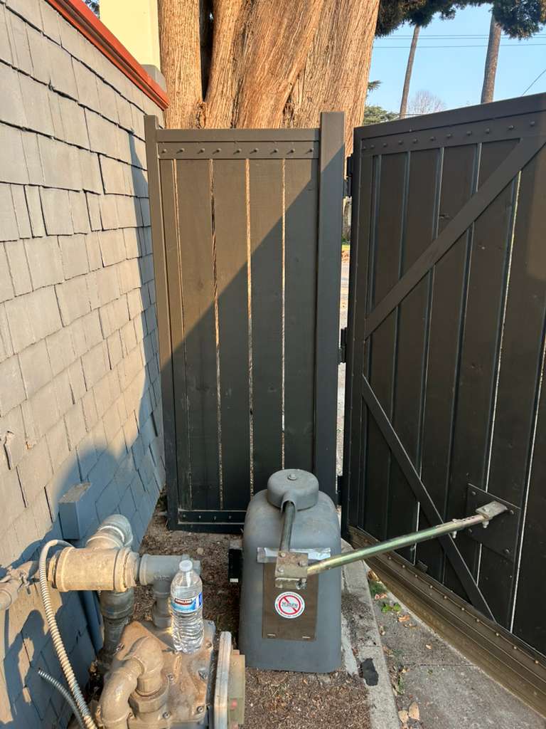 Automatic gate opener and water pump next to a wooden gate. in Koreatown, CA